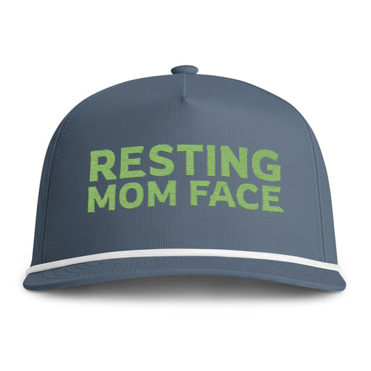 Image of an indigo hat with green embroidery reading "Resting Mom Face"
